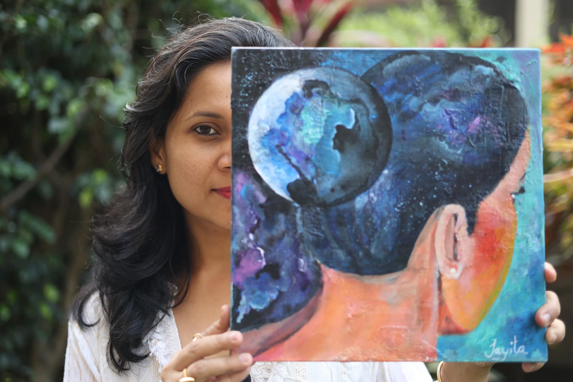 Jayita Dana holding a visionary artwork that partially frames her face