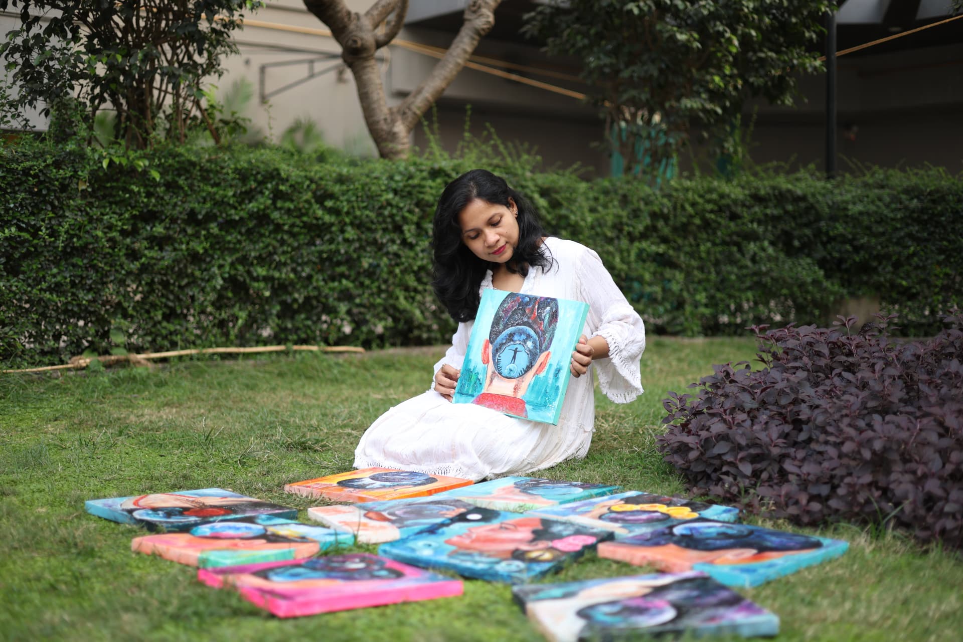 Jayita Dana sitting on grass holding a finished artwork