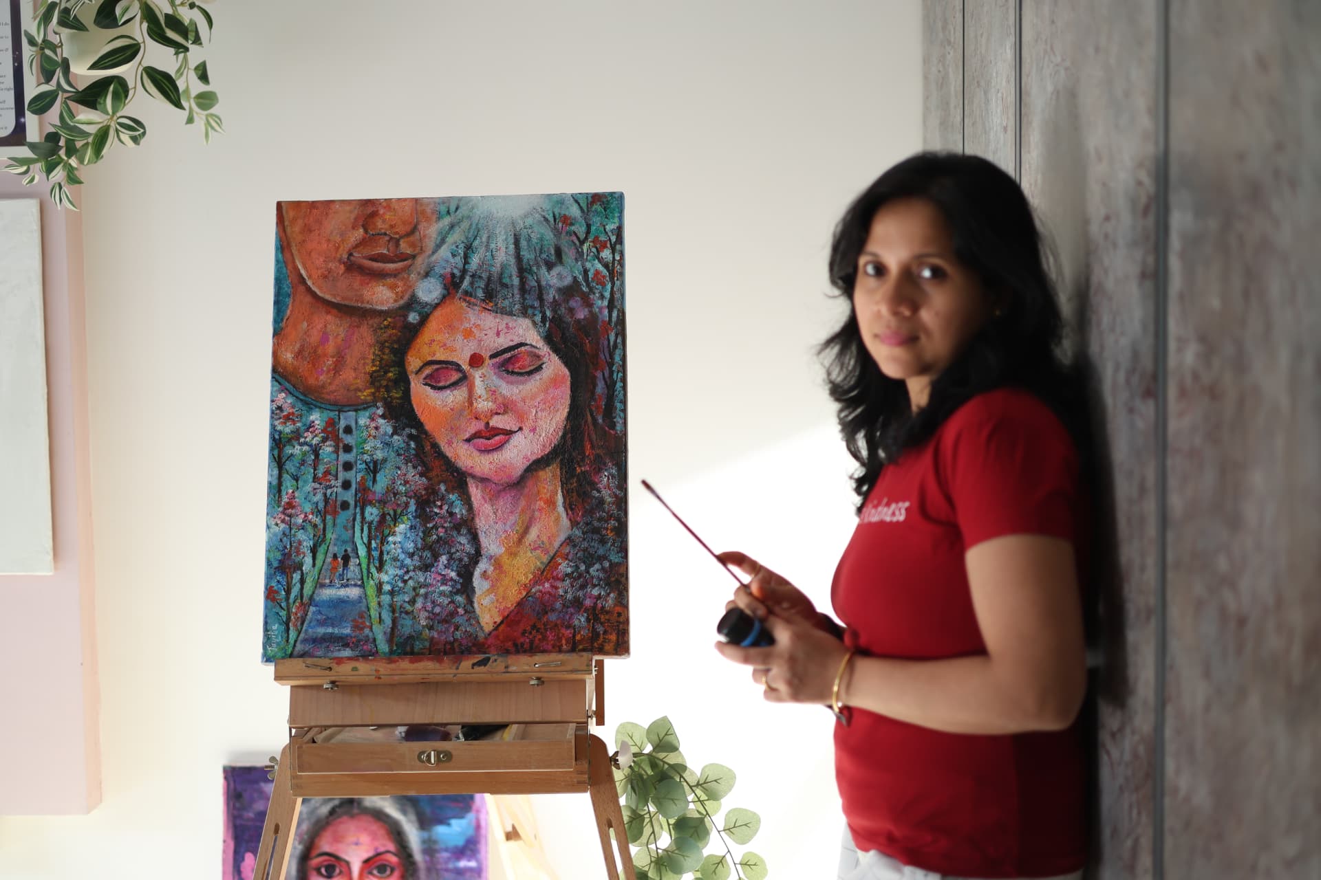 Jayita Dana beside a finished visionary portrait on her easel